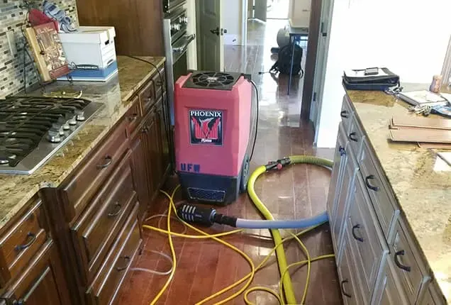 Air movers drying a kitchen slab after a supply-line leak in Watson