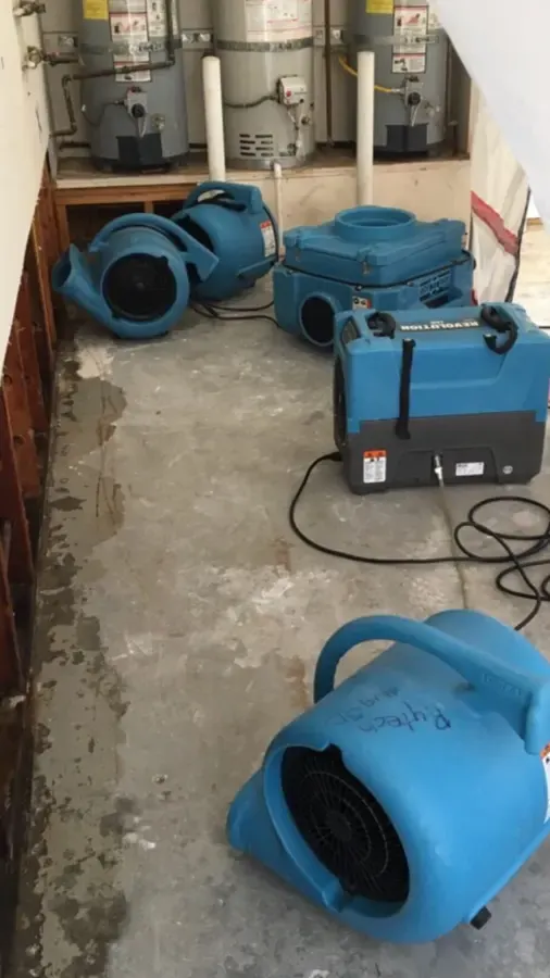 Dehumidifier and air movers drying a gutted Denham Springs room